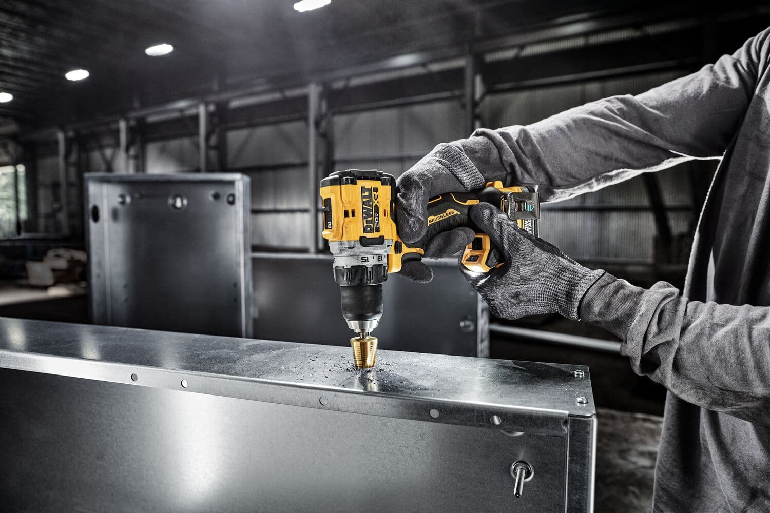 Una persona con guantes utiliza un taladro inalámbrico DEWALT para perforar una hoja de metal en un entorno industrial.