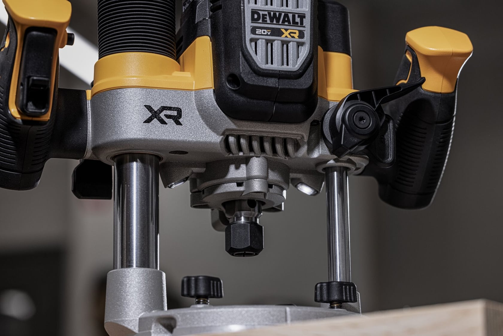 Close-up view of a DEWALT 20V XR cordless router with ergonomic handles, positioned on a wooden surface.