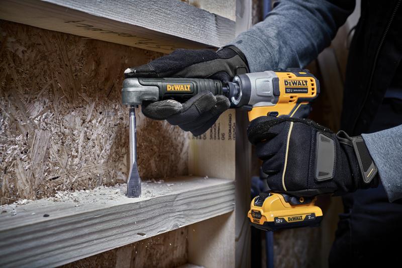 Una persona con guantes usa un taladro inalámbrico DEWALT de 12V con un accesorio de ángulo recto para perforar una tabla de madera, con virutas de madera visibles alrededor del área de trabajo.