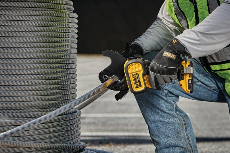 Una persona con guantes y chaleco de seguridad está usando una herramienta de corte de cables inalámbrica DEWALT para cortar una cuerda de alambre gruesa. Grandes bobinas de cuerda de alambre son visibles en el fondo.