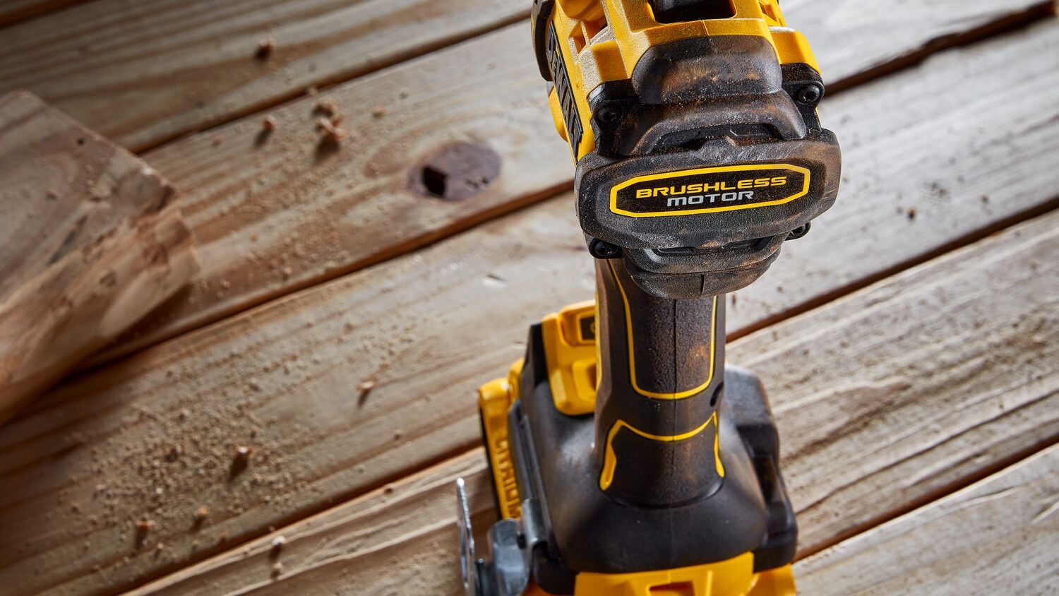Vista en primer plano de un taladro inalámbrico DEWALT con motor sin escobillas, colocado sobre una superficie de madera con virutas alrededor.
