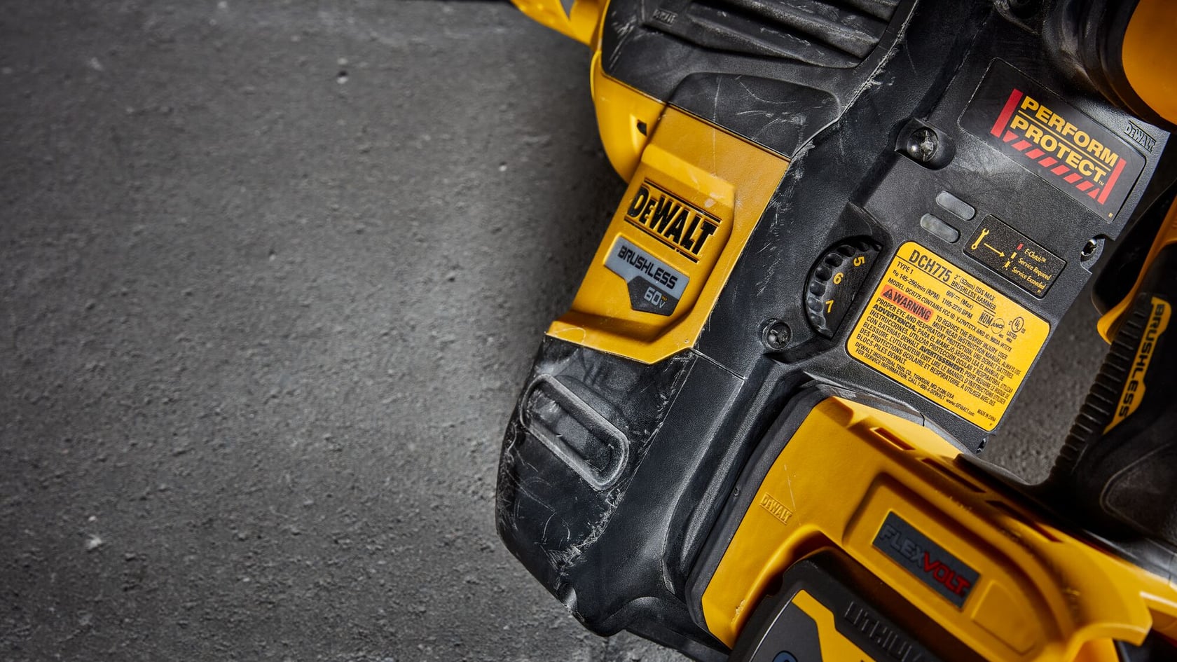 Primer plano de una herramienta eléctrica inalámbrica DEWALT, mostrando parte del mango, el paquete de batería y etiquetas informativas, incluyendo 'BRUSHLESS 60V' y 'PERFORM & PROTECT.' La herramienta está sobre una superficie gris rugosa.