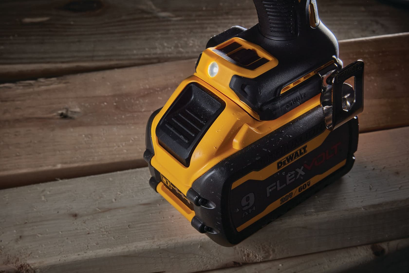 Primer plano de una herramienta eléctrica inalámbrica DEWALT, con una batería FLEXVOLT de 9Ah, colocada sobre una superficie de madera.