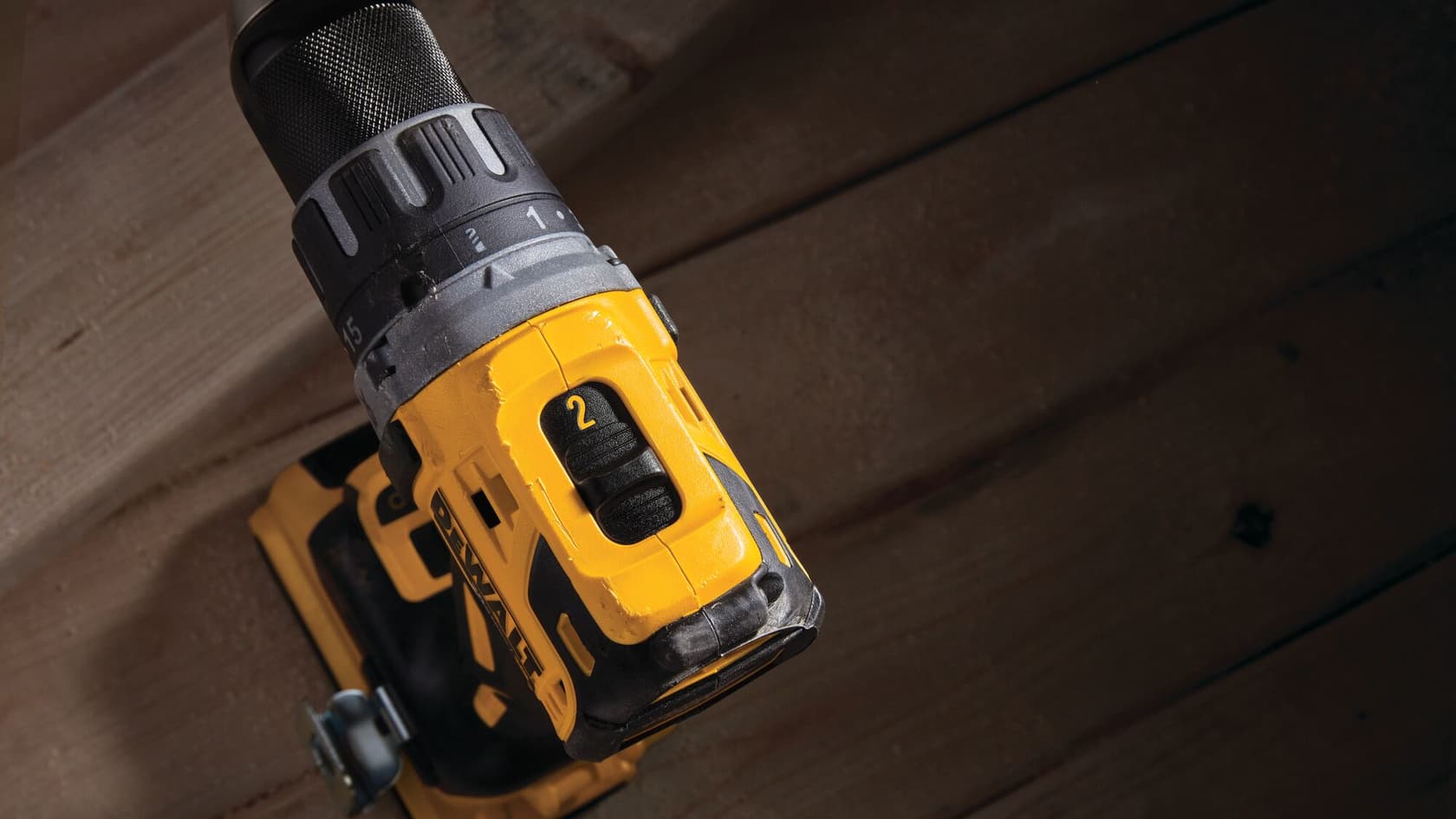 Primer plano de un taladro eléctrico inalámbrico amarillo y negro de DEWALT apoyado sobre una superficie de madera.