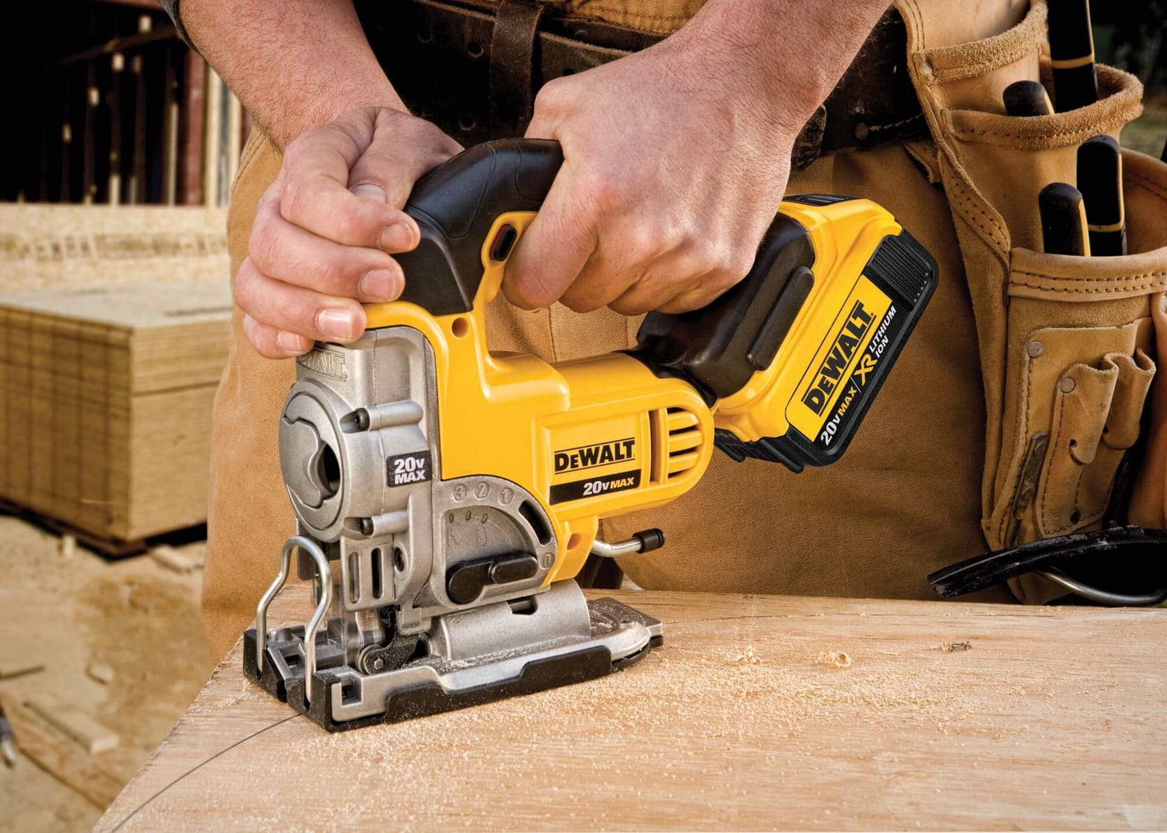 Vista de cerca de una persona usando una caladora inalámbrica amarilla DEWALT 20V MAX para cortar madera, con un cinturón de herramientas de carpintero visible en el fondo.